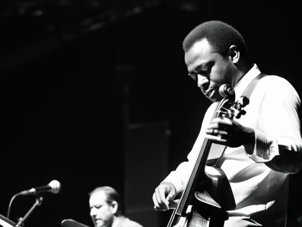 Fotografía en blanco y negro de una banda de jazz fusion en el escenario, destacando las manos del bajista tocando el bajo eléctrico